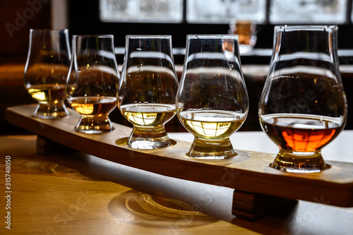 Scotch whisky, tasting glasses with variety of single malts or blended whiskey spirits on distillery tour in Scotland photo