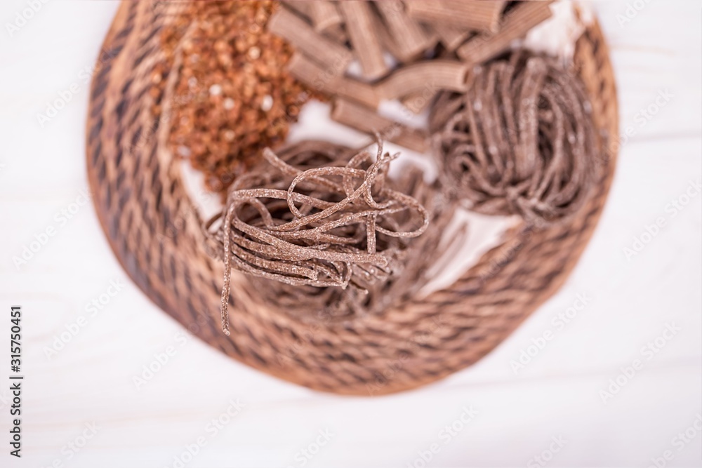 Brown raw buckwheat pasta, noodles and buckwheat groats on a white background. Gluten free concept. Copy space
