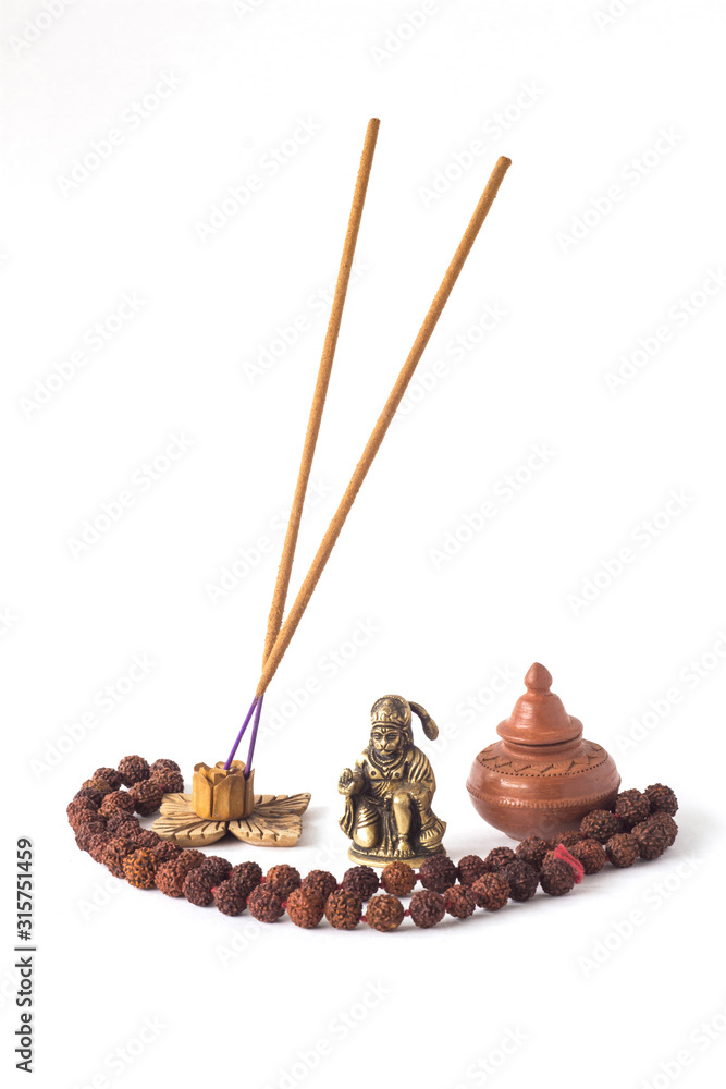 red rosary from Rudraksha, a copper figurine of the Indian deity Hanuman, a clay vessel with a lid and incense sticks isolated on a white background red rosary from Rudraksha, a copper figurine of the Indian deity Hanuman, a clay vessel with a lid and incense sticks isolated on a white background