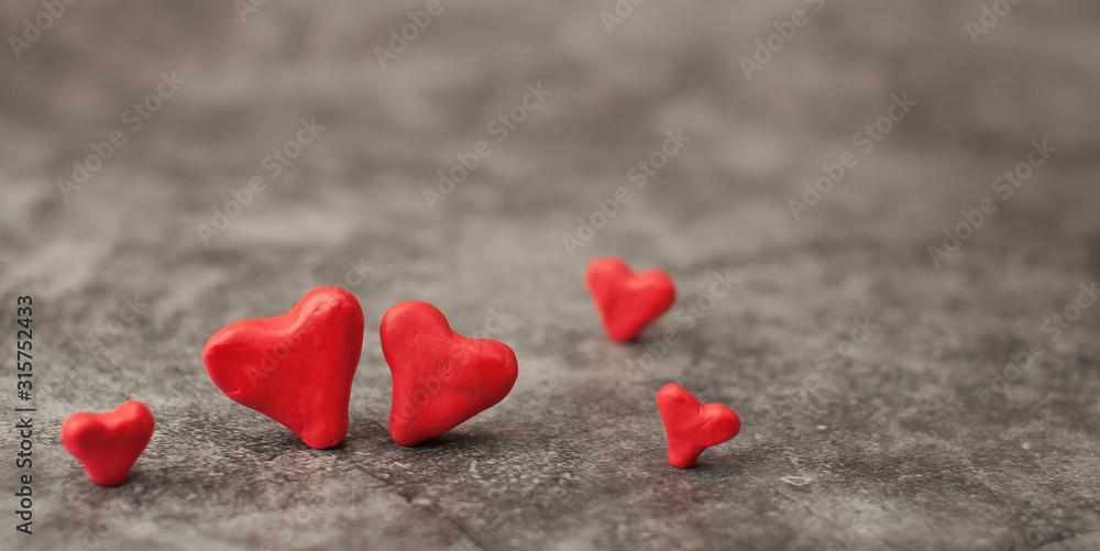 Obraz premium Festive background for Valentine's Day on a gray cement background with hearts in retro style from plasticine.