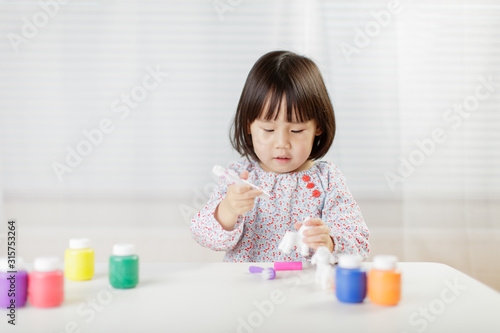 toddler girl watercolor painting on the animal toy at home against white background