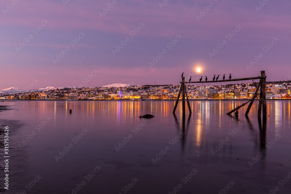 Amazing sunrise with amazing magenta color and moon over Tromso, Norway. Fisherman's building . Polar night. long shutter speed