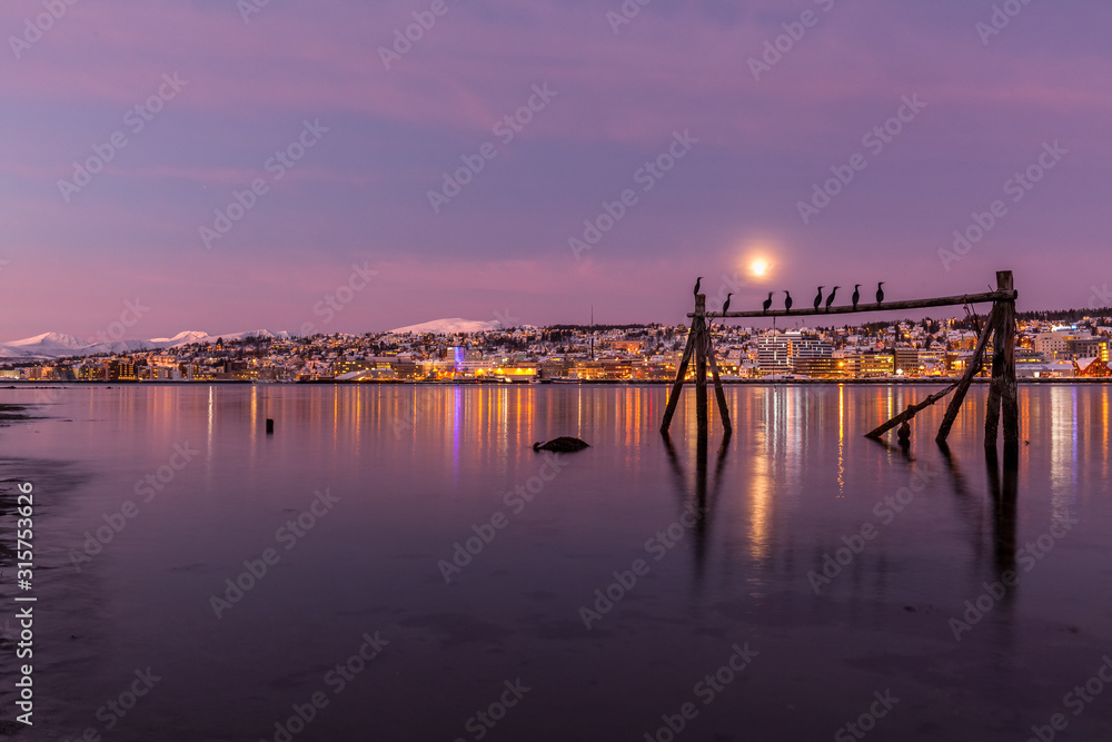 Obraz premium Amazing sunrise with amazing magenta color and moon over Tromso, Norway. Fisherman's building . Polar night. long shutter speed