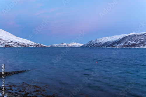 Amazing sunset with amazing magenta color over fjord Tromso, Norway. Polar night. long shutter speed