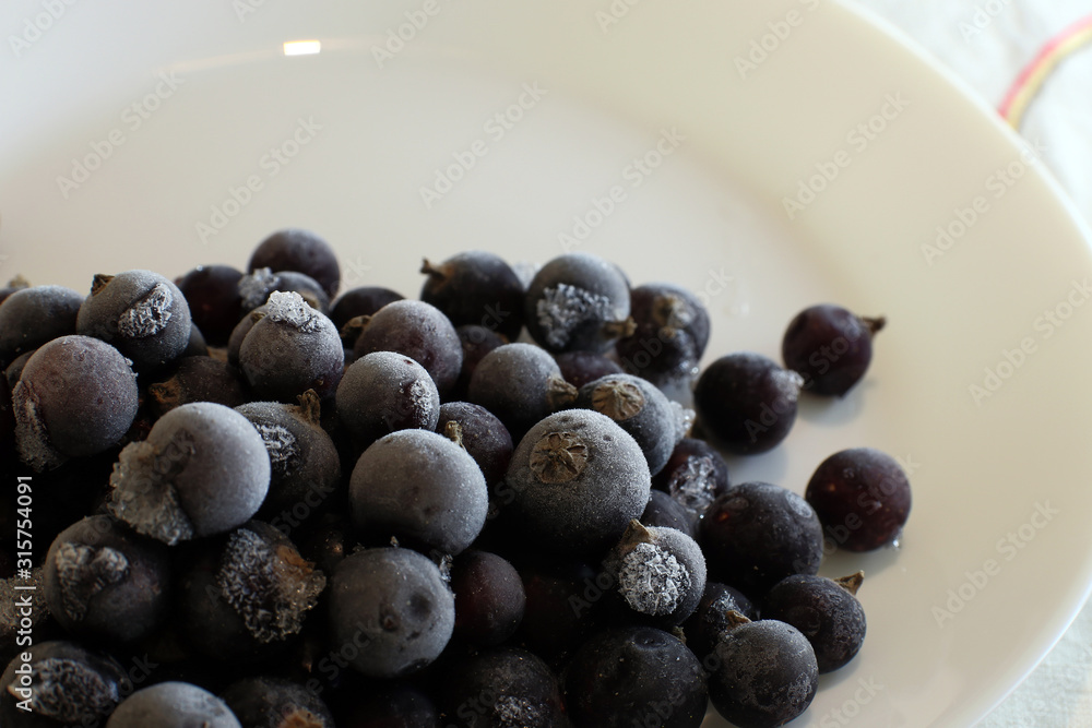 Frozen black currant on white plate. Harvesting fruit for the winter. Frozen black currant on white plate. Harvesting fruit for the winter.