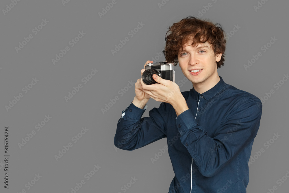 Copy Space for Text or product. Teenager boy standing isolated on grey taking photo on camera smiling joyful Copy Space for Text or product. Teenager boy standing isolated on grey taking photo on camera smiling joyful