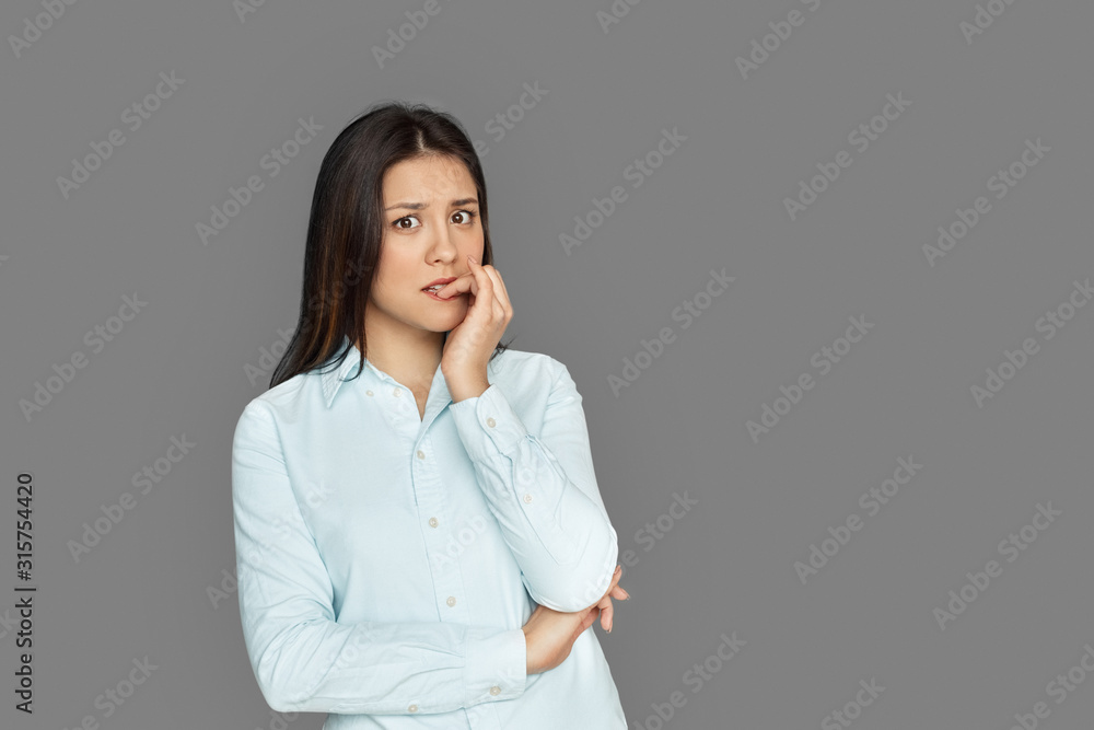Freestyle. Young woman standing isolated on grey biting nails nervous Freestyle. Young woman standing isolated on grey biting nails nervous
