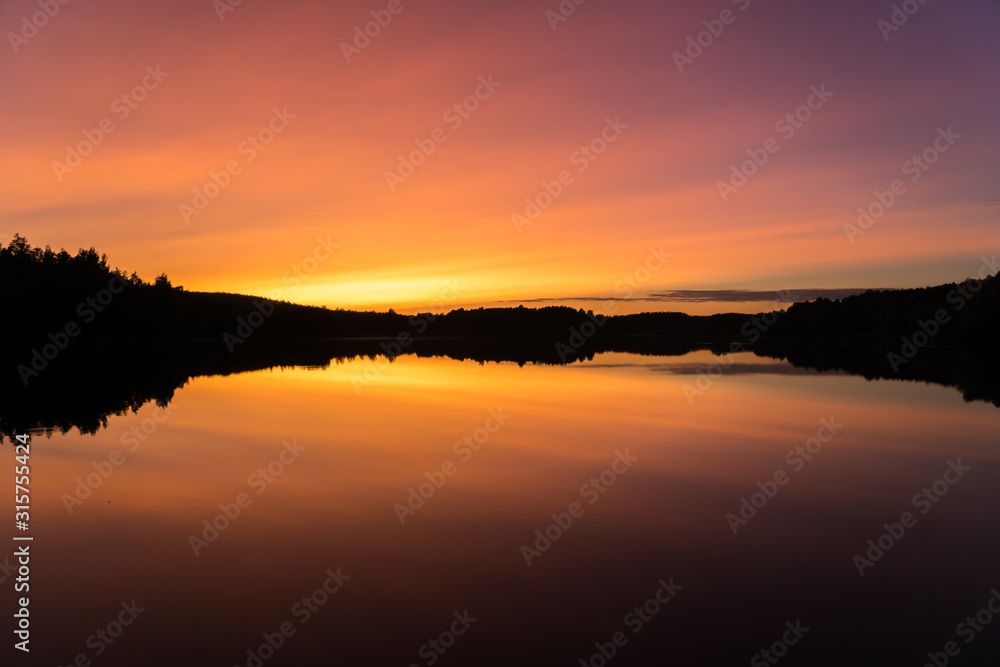 Peaceful orange, yellow and purple sunset over calm lake Peaceful orange, yellow and purple sunset over calm lake
