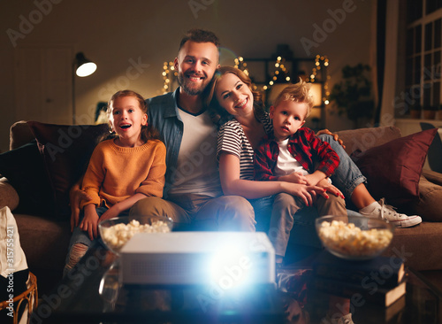 Bild auf Leinwand family mother father and children watching projector, TV, movies with popcorn in   evening   at home