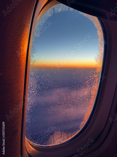 View from airplane window at orange and purple sunset. Golden hour. Travel and relax concept. Calm mood
