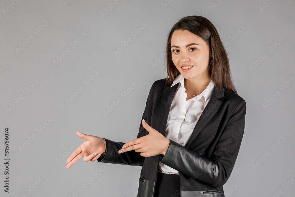 girl in black jacket on grey background pointing left girl in black jacket on grey background pointing left
