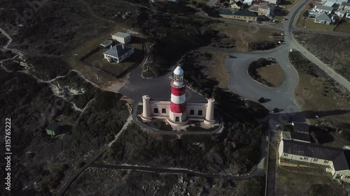 4K sunny summer aerial drone video of Cape Agulhas Lighthouse on southernmost tip of African continent peninsula near Indian Ocean coastal village L'Agulhas, Garden Route, Western Cape, South Africa