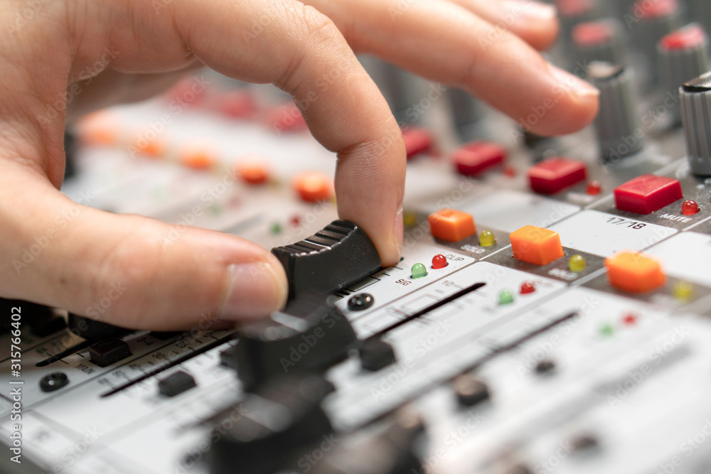 Fototapeta premium Close-up of a mixing console, hand equalizing audio channels. Professional recording studio. Working in recording studio .