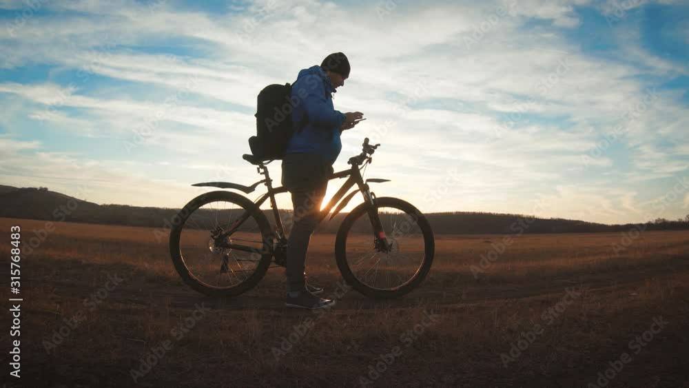 The silhouette of the mountain bicycle rider on the hill with bike at sunset. Sport, travel and active life concept. The silhouette of the mountain bicycle rider on the hill with bike at sunset. Sport, travel and active life concept.