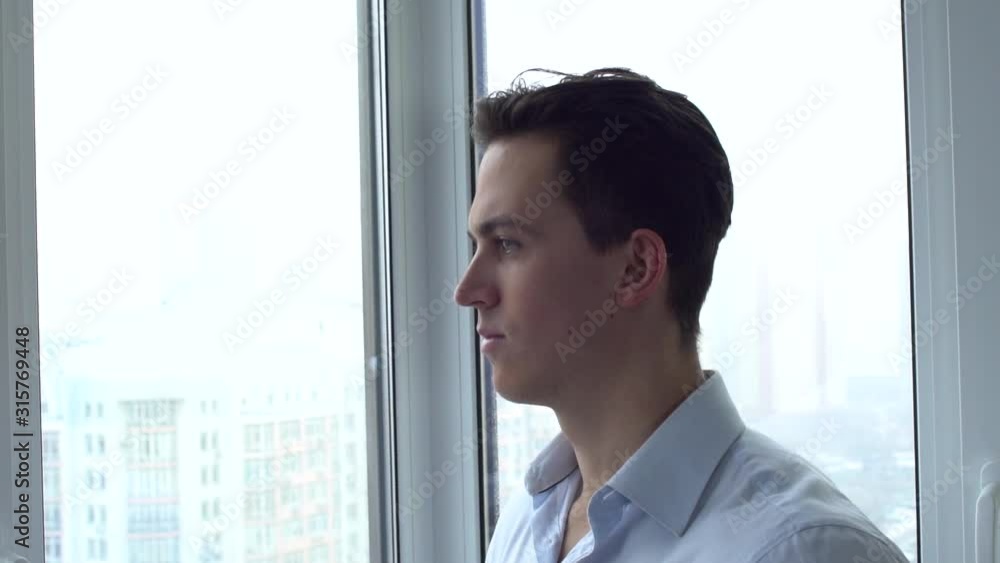 Business man standing near widow looking outside Business man standing near widow looking outside