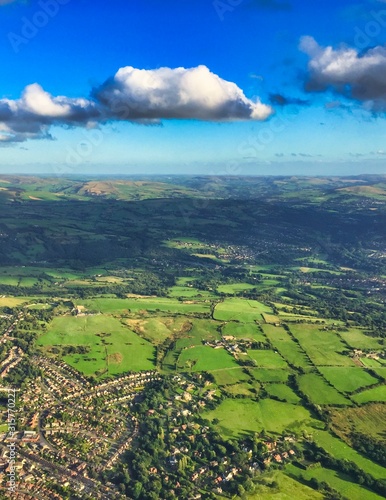 aerial view of English countryside in the sunshine with fluffy clouds and green fields
