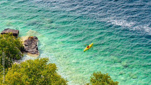 Fototapeta Naklejka Na Ścianę i Meble -  Unrecognizable woman silhouette kayaking in the ocean. Beautiful rocky beach with crystal clear ocean waters.