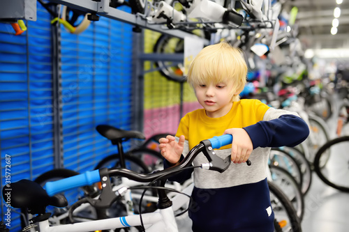 Little boy choosing bicycle in sport store.