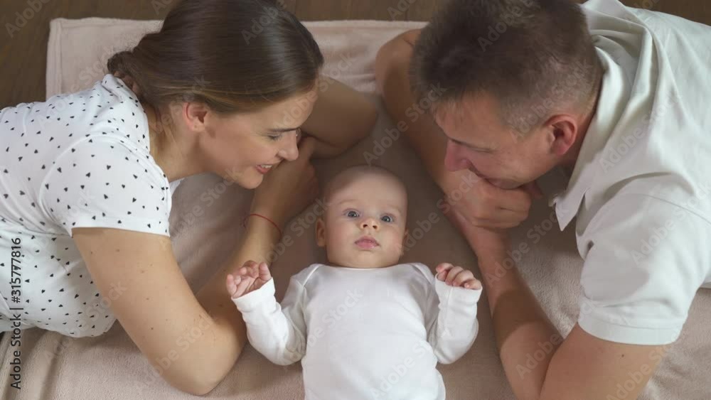 Smiling family in bed, where the cool face plan is dad, mom and little son. Smiling family in bed, where the cool face plan is dad, mom and little son.