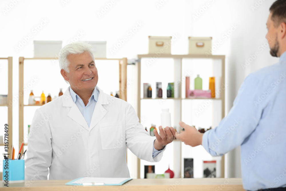 Pharmacist giving medicine to customer in drugstore Pharmacist giving medicine to customer in drugstore