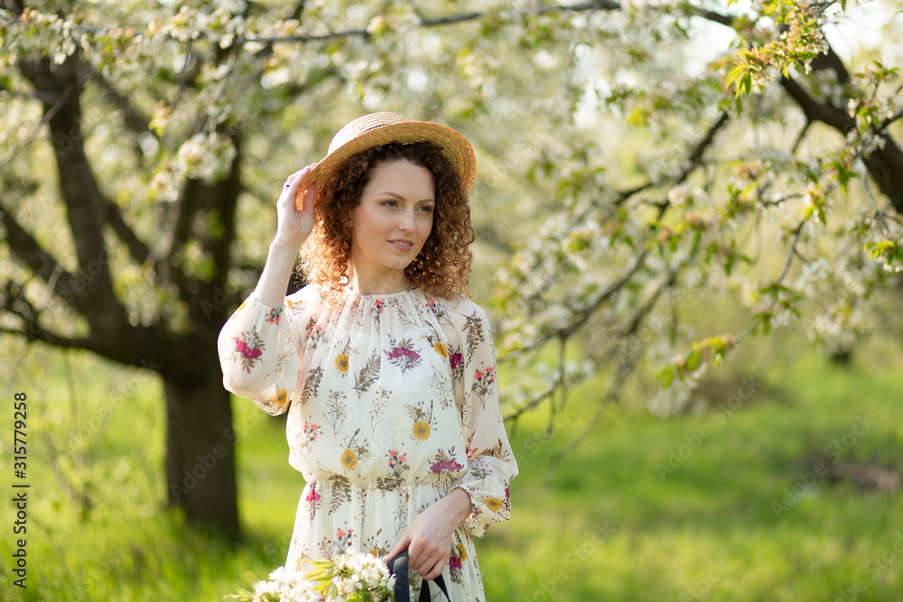 A gorgeous girl walks in a flowering spring garden. The concept of unity of man with nature A gorgeous girl walks in a flowering spring garden. The concept of unity of man with nature