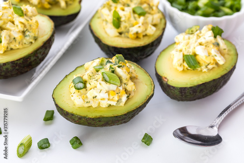A top down view of egg salad in avocado boats ready for eating.