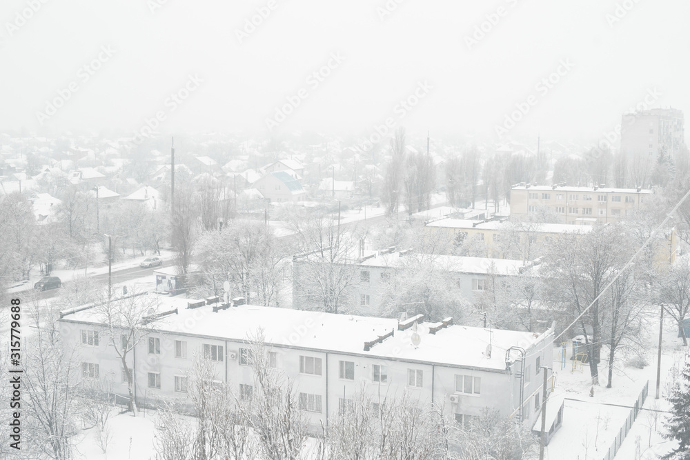 Fototapeta premium Snow blizzard in a small town. Everything is covered with white snow.