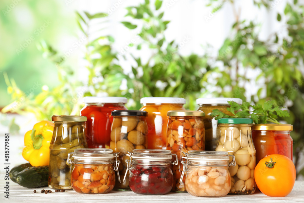 Glass jars of different pickled vegetables on white wooden table Glass jars of different pickled vegetables on white wooden table