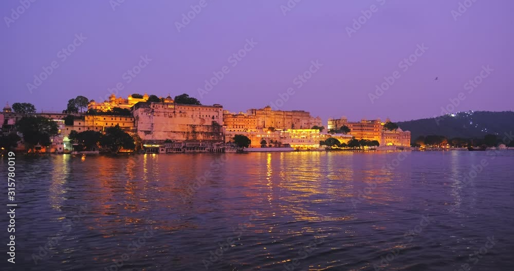 Udaipur City Palace and Lal ghat on bank of lake Pichola with water ripples - Rajput architecture of Mewar dynasty rulers of Rajasthan. Sunset at Udaipur, India. Udaipur City Palace and Lal ghat on bank of lake Pichola with water ripples - Rajput architecture of Mewar dynasty rulers of Rajasthan. Sunset at Udaipur, India.