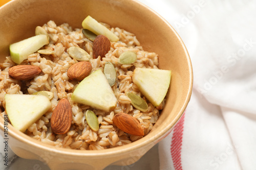 Tasty oatmeal with apples and almonds on table, closeup. Healthy breakfast