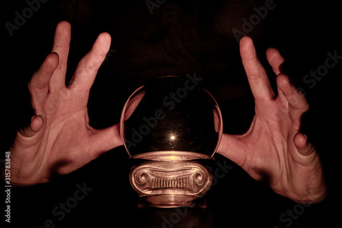 Hands over crystal ball in dark room, crystal ball gazing, crystal ball psychic, crystal ball fortune telling, crystal ball scrying, crystal ball object of power, seance with crystal ball 5