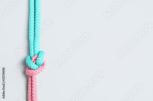Colorful ropes tied together with knot isolated on white, top view. Unity concept