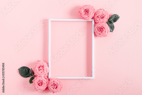 Beautiful flowers composition. Blank frame for text, pink rose flowers on pastel pink background. Valentines Day, Easter, Birthday, Happy Women's Day, Mother's day. Flat lay, top view, copy space
