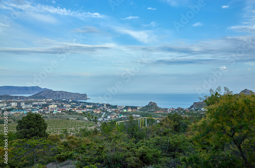 View of the city of Sudak and the Black Sea coast from a height. Mountain coniferous forest, Republic of Crimea