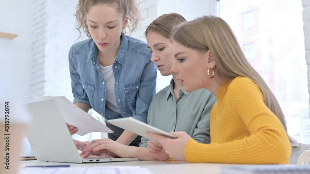 Creative Designers working on Laptop with Documents and Tablet Creative Designers working on Laptop with Documents and Tablet