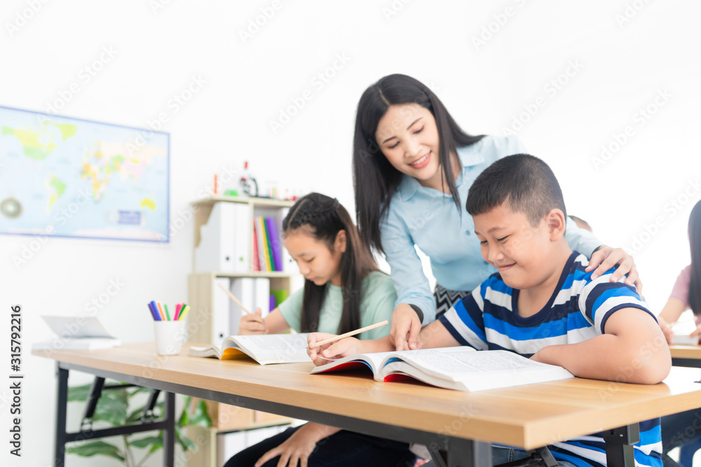 blurred asian students studying and do work with teacher in classroom, asian teacher teaching and explaining about how to do homework, happiness elementary school blurred asian students studying and do work with teacher in classroom, asian teacher teaching and explaining about how to do homework, happiness elementary school