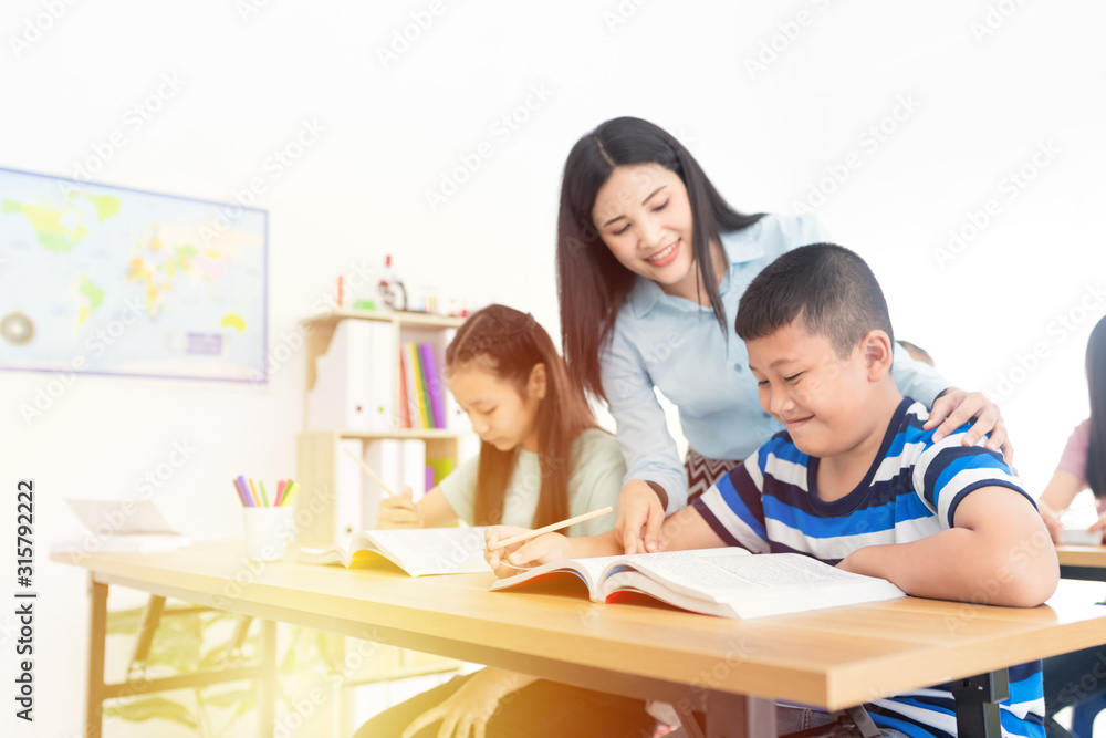 blurred asian students studying and do work with teacher in classroom, asian teacher teaching and explaining about how to do homework, happiness elementary school blurred asian students studying and do work with teacher in classroom, asian teacher teaching and explaining about how to do homework, happiness elementary school