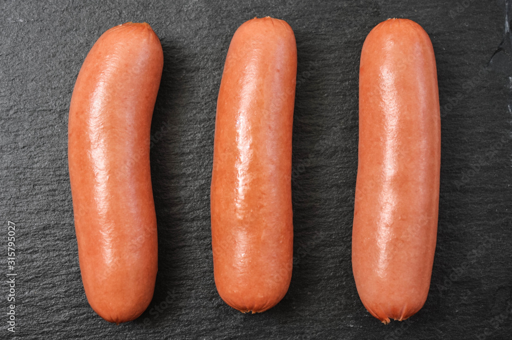 Three cooked sausages on a black basalt background Three cooked sausages on a black basalt background