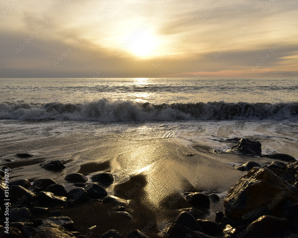 Fototapeta premium A sunset reflecting in the sea water with big waves in the front