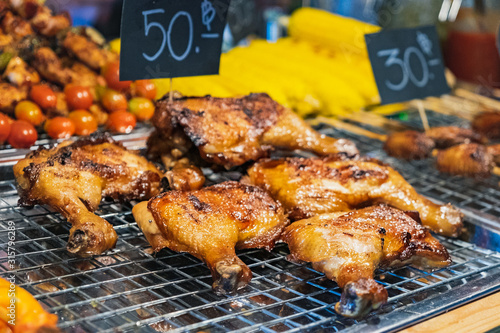 Chicken with a crispy crust was grilled by a street vendor at Thai street night market. Deep fried snacks, fresh and hot Thai food.