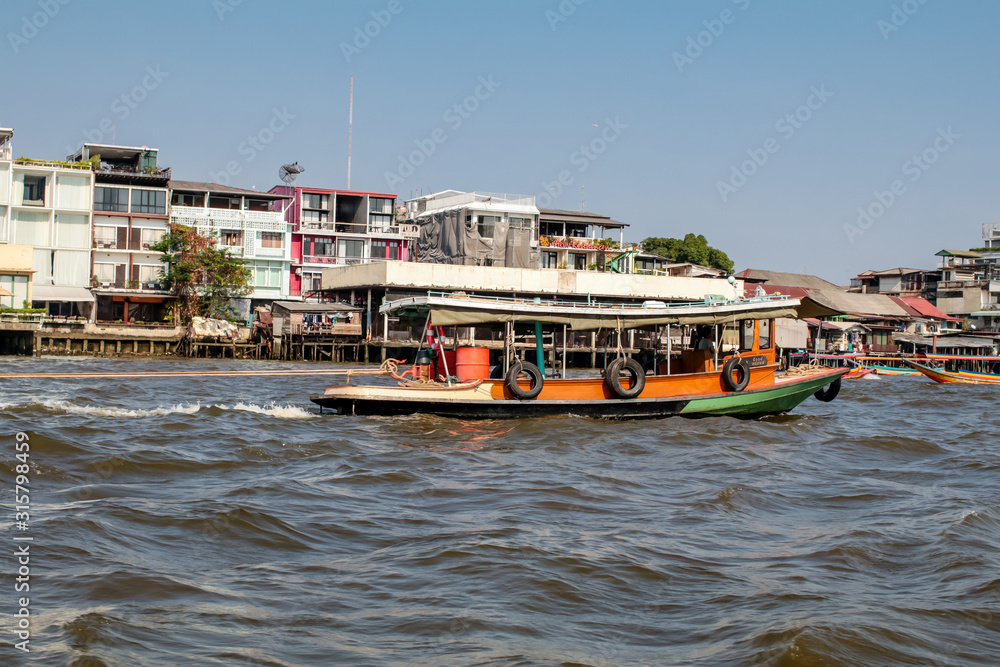 BANGKOK,THAILAND -January 16,2020 Boat in chaopaya river.Passengers on the shuttle boat ,The boat at Chaopaya riverside in Bangkok Thailand,River font and city landscape blue sky horizontal line, ,sel BANGKOK,THAILAND -January 16,2020 Boat in chaopaya river.Passengers on the shuttle boat ,The boat at Chaopaya riverside in Bangkok Thailand,River font and city landscape blue sky horizontal line, ,sel