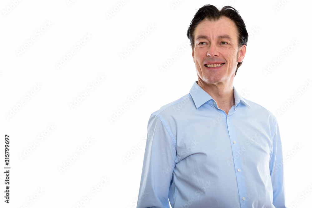 Studio shot of mature happy businessman smiling while thinking Studio shot of mature happy businessman smiling while thinking