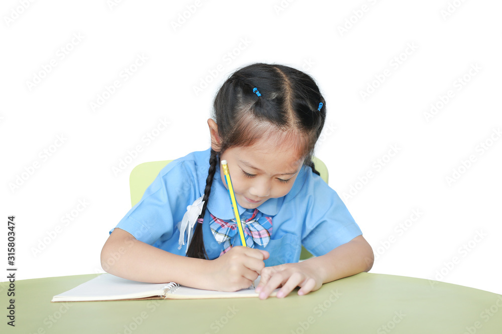 Close-up Asian little girl in school uniform writing on notebook at desk isolated on white background. Schoolgirl and Education concept. Close-up Asian little girl in school uniform writing on notebook at desk isolated on white background. Schoolgirl and Education concept.