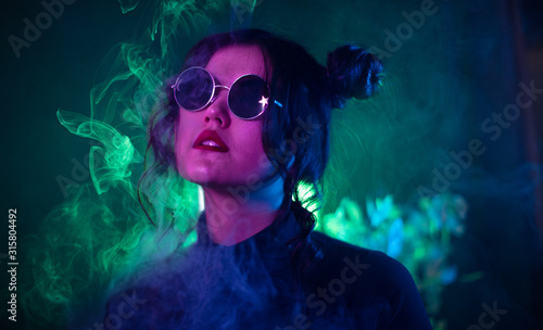 Closeup studio portrait of Oriental girl in creative light with flowing smoke on dark background