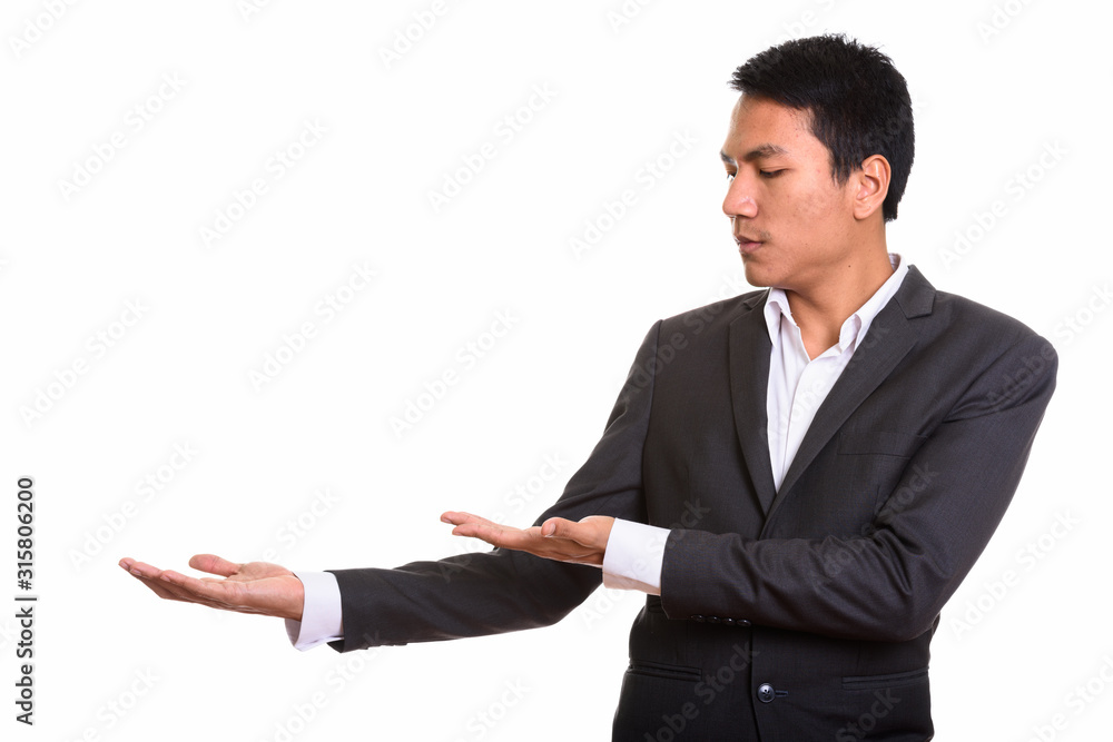 Studio shot of young Asian businessman showing something Studio shot of young Asian businessman showing something