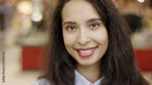 Wallpaper Mural Close up portrait shot of beautiful young woman smiling happily looking positive and joyful standing in supermarket with people moving in blurred background. Torontodigital.ca