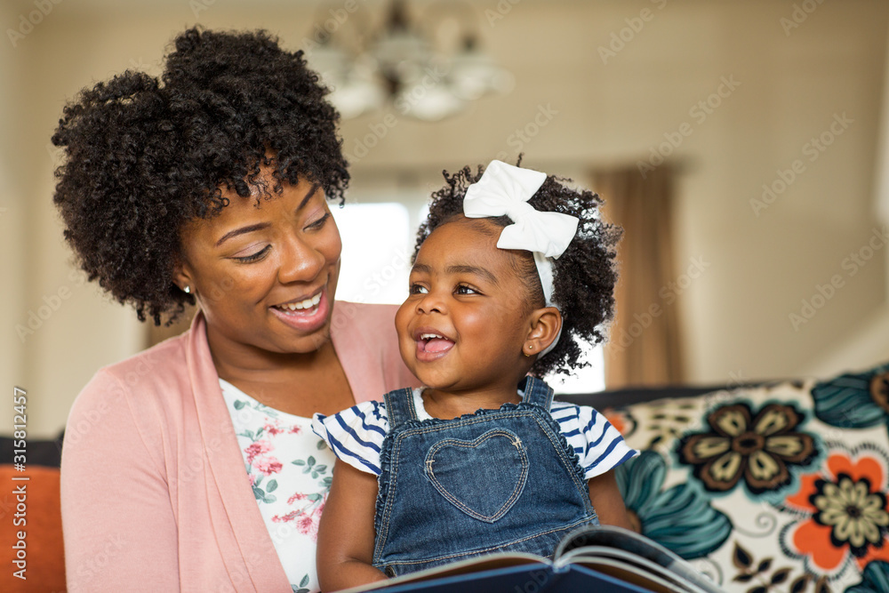 Naklejka premium Mother reading a book to her little girl.