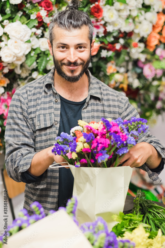 Florist at work: young man making fashion modern bouquet of different flowers