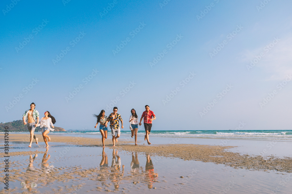 A group of happy friends who play fun on the white sand beach amid the blue sky.. - obrazy, fototapety, plakaty 