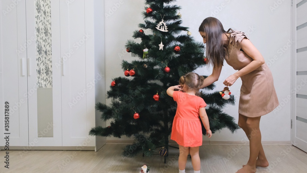 family, winter holidays and people concept - happy mother and little daughter decorating christmas tree at home family, winter holidays and people concept - happy mother and little daughter decorating christmas tree at home
